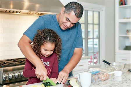 Father helping daughter chop vegetables in kitchen Stock Photo - Premium Royalty-Free, Code: 614-08383709