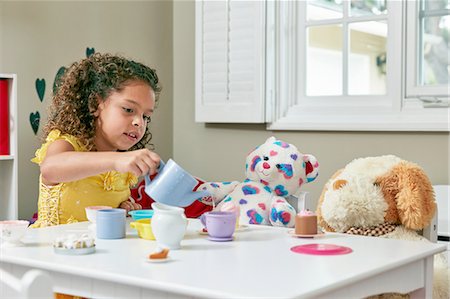 simsearch:614-07768068,k - Girl in playroom sitting at table serving tea from toy tea set to soft toys Stock Photo - Premium Royalty-Free, Code: 614-08383729