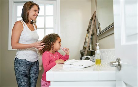 Mother and daughter in bathroom at sink brushing teeth Stock Photo - Premium Royalty-Free, Code: 614-08383732
