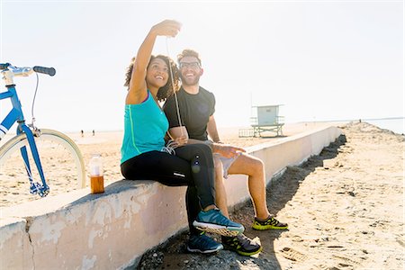 Couple sitting on wall taking self portrait using smartphone Stock Photo - Premium Royalty-Free, Code: 614-08392495