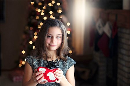 polka dot gift wrap - Portrait of girl in front of christmas tree holding gift looking at camera smiling Stock Photo - Premium Royalty-Free, Code: 614-08392721