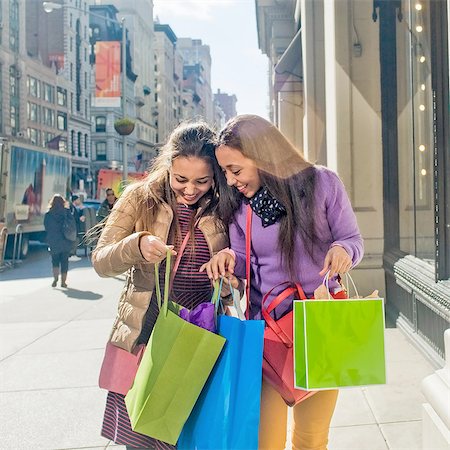 shopping women - Young female adult twins looking into shopping bags outside city shop Stock Photo - Premium Royalty-Free, Code: 614-08392746