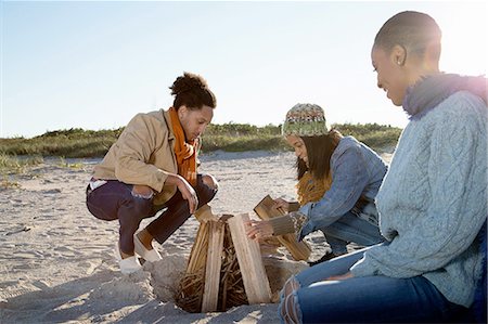 squatting man - Three friends on beach, preparing camp fire Stock Photo - Premium Royalty-Free, Code: 614-08487950