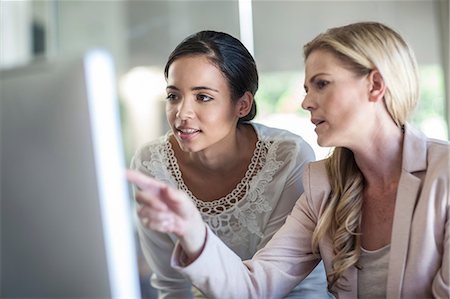 Businesswomen looking at personal computer at office desk Stock Photo - Premium Royalty-Free, Code: 614-08578365