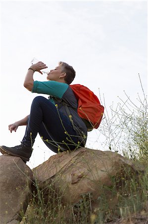 Woman hiker sitting on top of rocks drinking water from bottle Stock Photo - Premium Royalty-Free, Code: 614-08578823