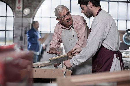 sawing - Senior carpenter explaining sawing to trainee in workshop Stock Photo - Premium Royalty-Free, Code: 614-08641354