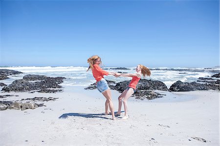 pre teen girl smiling on beach - Girl and young woman holding hands and spinning each other around on beach, Cape Town, South Africa Stock Photo - Premium Royalty-Free, Code: 614-08641758