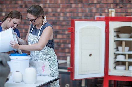 Female potter pouring ceramic glaze into bucket in workshop Stock Photo - Premium Royalty-Free, Code: 614-08684986