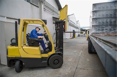 Forklift driver loading pallet onto truck at packaging factory Stock Photo - Premium Royalty-Free, Code: 614-08726508
