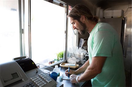 Man in fast food trailer writing order on notepad Stock Photo - Premium Royalty-Free, Code: 614-08726535
