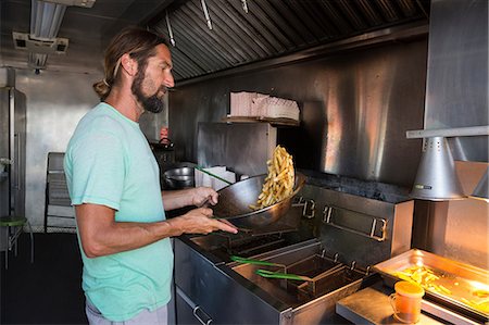 Man cooking food in fast food trailer Stock Photo - Premium Royalty-Free, Code: 614-08726530