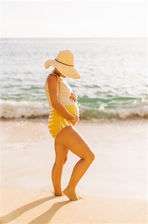 pregnant woman in swimsuit - Pregnant mid adult woman wearing swimming costume holding stomach Makua beach, Hawaii, USA Stock Photo - Premium Royalty-Free, Code: 614-08726745