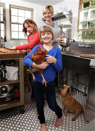 family and pets - Mother and daughters in kitchen preparing folder, younger daughter holding pet chicken Stock Photo - Premium Royalty-Free, Code: 614-08768441