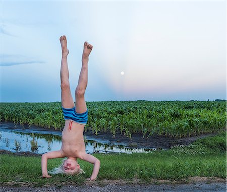 flexible (people or objects with physical bendability) - Boy wearing shorts doing handstand in rural area Stock Photo - Premium Royalty-Free, Code: 614-08827139