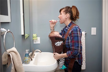 Mother with baby boy in baby sling, brushing teeth Stock Photo - Premium Royalty-Free, Code: 614-08827191