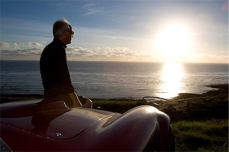 Older Man views sunset from car bonnet Stock Photo - Premium Royalty-Free, Code: 614-08866521