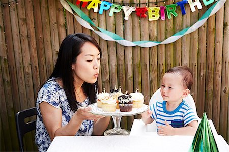 Mother blowing out candles on baby boy's birthday cakes Stock Photo - Premium Royalty-Free, Code: 614-08876092