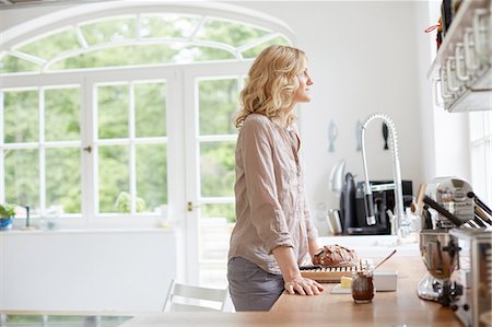 simsearch:614-06897927,k - Mid adult woman standing at kitchen counter, looking out of window Foto de stock - Sin royalties Premium, Código: 614-08877700