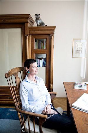 single woman sitting on a chair home - Woman sitting at desk Stock Photo - Premium Royalty-Free, Code: 614-08877893