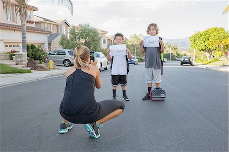 parenthood - Mother photographing two schoolboy sons holding papers with handwritten school grade Stock Photo - Premium Royalty-Free, Code: 614-08878282