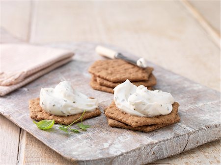 Garlic and herb soft cheese on hexagon crackers on whitewashed cutting board Stock Photo - Premium Royalty-Free, Code: 614-08878735