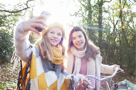 Teenage girls in forest using smartphone to take selfie smiling Stock Photo - Premium Royalty-Free, Code: 614-08879021