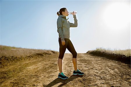 simsearch:614-09078761,k - Silhouetted female runner drinking from water bottle on dirt track Stock Photo - Premium Royalty-Free, Code: 614-08879151