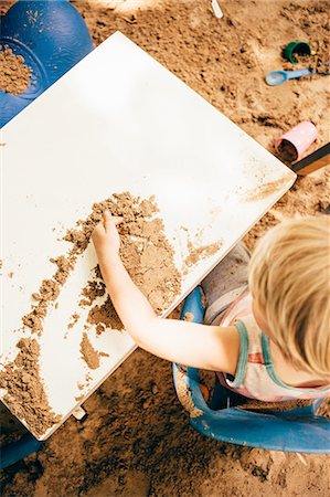 Overhead boy of boy sitting at table in sandpit playing with sand Stock Photo - Premium Royalty-Free, Code: 614-08879270