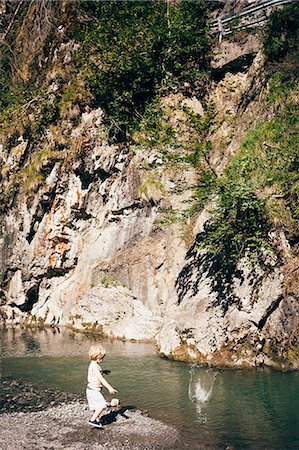 Full length side view of boy throwing stones into water, Dornbirn, Vorarlberg, Austria Stock Photo - Premium Royalty-Free, Code: 614-08879288