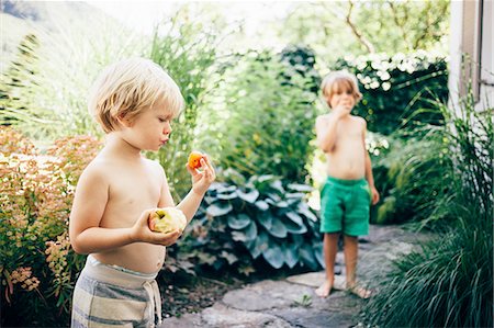 Boys on garden path eating apples and oranges, Bludenz, Vorarlberg, Austria Stock Photo - Premium Royalty-Free, Code: 614-08879282