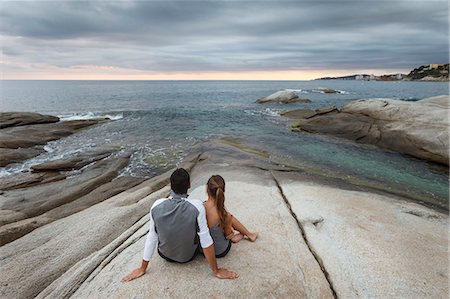 simsearch:6113-07790495,k - Couple relaxing on boulder by ocean Stock Photo - Premium Royalty-Free, Code: 614-08870164