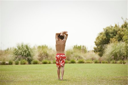 Boy in swimsuit walking in grassy field Stock Photo - Premium Royalty-Free, Code: 614-08870771