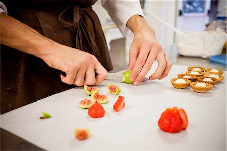 Baker slicing fruit in kitchen Stock Photo - Premium Royalty-Free, Code: 614-08871086