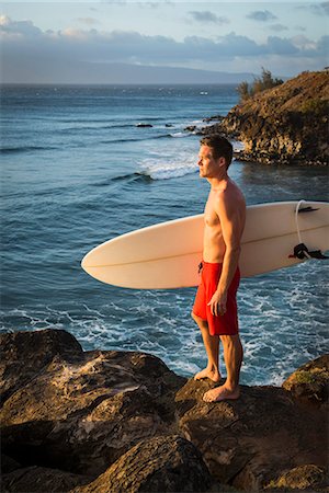 Surfer carrying board on beach Stock Photo - Premium Royalty-Free, Code: 614-08871420