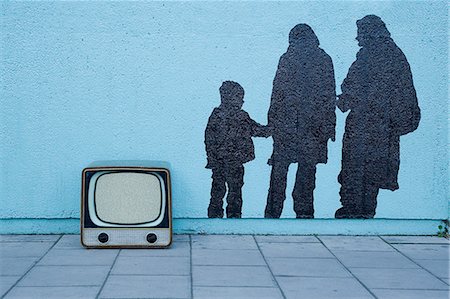 stenciling - Retro television by blue wall with mural of three people Stock Photo - Premium Royalty-Free, Code: 614-08871864