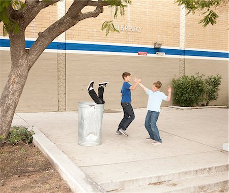 prank - Two boys bullying another, one boy in dustbin Stock Photo - Premium Royalty-Free, Code: 614-08872549