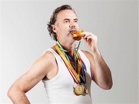 sports event - Mature man eating gold coin against white background Stock Photo - Premium Royalty-Free, Code: 614-08873582