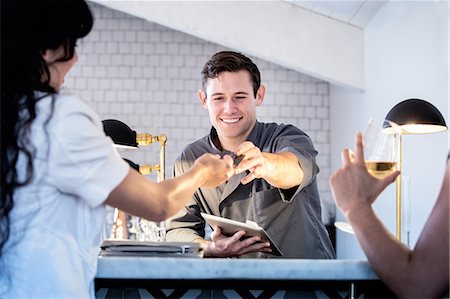 simsearch:6108-06907863,k - Barman serving customers at bar, barman using digital tablet to take payment Stock Photo - Premium Royalty-Free, Code: 614-08884593