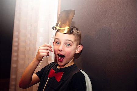 preteen open mouth - Portrait of boy holding bow tie and top hat stick masks posing at party Foto de stock - Sin royalties Premium, Código: 614-08884769