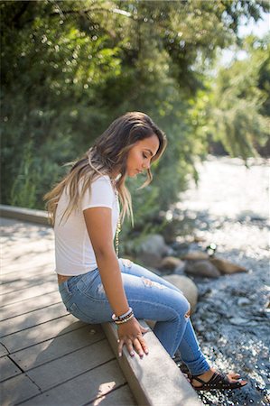 Teenage girl sitting on footbridge gazing at river Stock Photo - Premium Royalty-Free, Code: 614-08884990