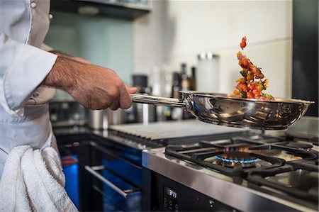 Chef holding frying pan, cooking food over stove, close-up Stock Photo - Premium Royalty-Free, Code: 614-08885098