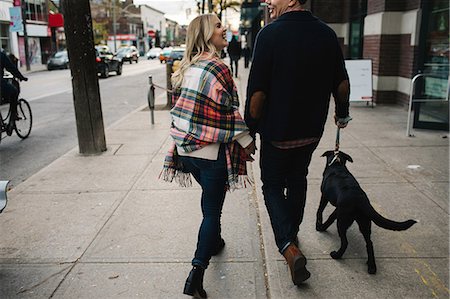 people walking in the street - Young couple walking dog along street, rear view Stock Photo - Premium Royalty-Free, Code: 614-08880928