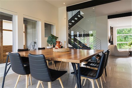 American walnut wood dining table and black leather sitting chairs with ash wood legs in the dining room inside a modern cube style home, Quebec, Canada Stock Photo - Premium Royalty-Free, Code: 614-08881123