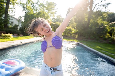 simsearch:614-06896861,k - Boy in seashell bikini top dancing by outdoor swimming pool Stock Photo - Premium Royalty-Free, Code: 614-08908364