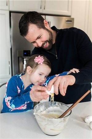 Mid adult man and daughter cracking egg into mixing bowl together at kitchen counter Stock Photo - Premium Royalty-Free, Code: 614-08908394