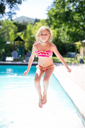 Portrait of girl jumping into outdoor swimming pool Stock Photo - Premium Royalty-Free, Code: 614-08908480
