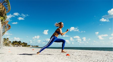 Young woman training, running between training cones on beach Stock Photo - Premium Royalty-Free, Code: 614-08908530