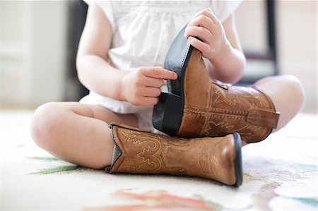 Neck down view of female toddler sitting on floor wearing cowboy boots Stock Photo - Premium Royalty-Free, Code: 614-08926086