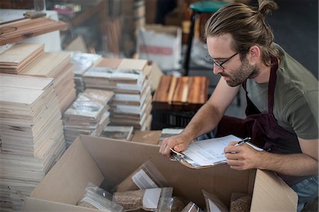 small business, inventory - Man with clipboard checking boxed products in factory Stock Photo - Premium Royalty-Free, Code: 614-08926144