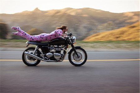Man wearing onesie lying on front riding motorcycle, Malibu Canyon, California, USA Stock Photo - Premium Royalty-Free, Code: 614-08926281